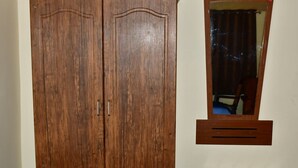 Une armoire en bois à deux portes, avec un miroir au-dessus.