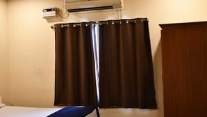 Une chambre avec un lit, un appareil de climatisation, un rideau et une porte en bois.