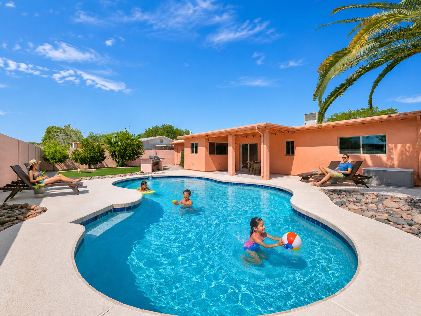Una piscina de diseño curvo, rodeada de sillas de descanso y una zona de terraza cubierta.