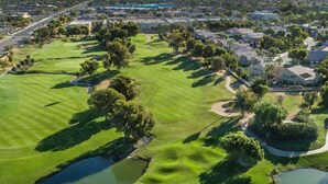 Luftaufnahme eines Golfplatzes mit mehreren Wasserschutzhindernissen, umgeben von Wohngebieten.