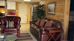 Ein Wohnzimmer mit einer Ledersofa, einem roten Sessel, einem Couchtisch und einer Holzwand.