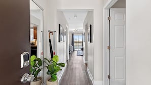 A hallway with a wooden floor, white walls, and a door at the end. - Riverfront Rhythm by Avantstay Shared Pool + Balcony + River Views Walk to Broadway + Germantown (Nashville)
