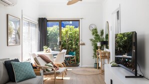 Un salon moderne comprenant un canapé, des fauteuils, un téléviseur et un coin repas avec une table et des chaises.