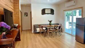 A modern kitchen with wooden cabinetry, a dining area with a table and chairs, a built-in oven, and a large window.