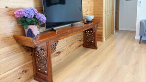 A wooden TV stand with a flat-screen TV, a potted plant, and a bowl.