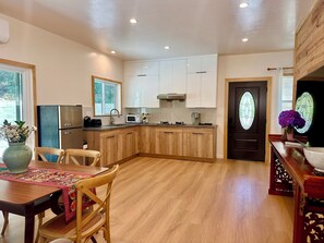 A modern kitchen with wooden cabinets, a dining area with a table and chairs, and a decorative door with stained glass.