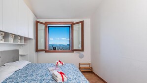 Ein Hotelzimmer mit einem Bett, einem Fenster mit Blick, einem kleinen Tisch und einem Spiegel.