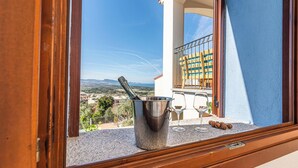 Ein Balkon mit Blick auf die Landschaft, ein Metalleimer, zwei Weingläser und eine Weinflasche.