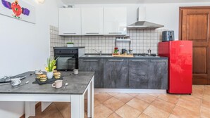 Eine moderne Küche mit weißen Schränken, einem roten Kühlschrank und einer gefliesten Spritzschutzwand.