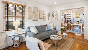 A modern living room with a grey sofa, a round coffee table, and a dining area with a white table and chairs. - Brooks Avenue by Avantstay Walk to Venice Beach + Boardwalk Firepit Terrace + EV Charger (Venice)