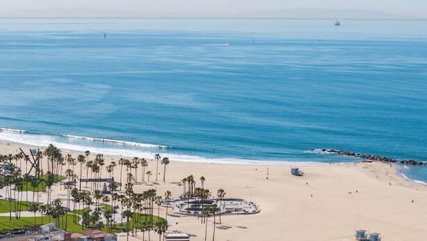 A beach with palm trees, a lifeguard tower, and a pier extending into the ocean. - Brooks Avenue by Avantstay Walk to Venice Beach + Boardwalk Firepit Terrace + EV Charger (Venice)