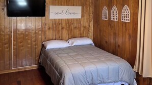 Un dormitorio con cama, ventilador de techo, televisor montado, paneles de madera y un cartel que dice 'sweet dreams'.