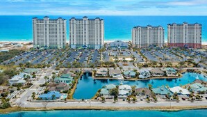 Un resort con múltiples edificios altos, un puerto deportivo y vista a la playa.