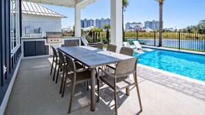 Un patio exterior con piscina, una parrilla y vistas del horizonte de la ciudad.