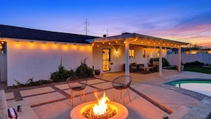 Un patio con una chimenea, asientos exteriores y una piscina.