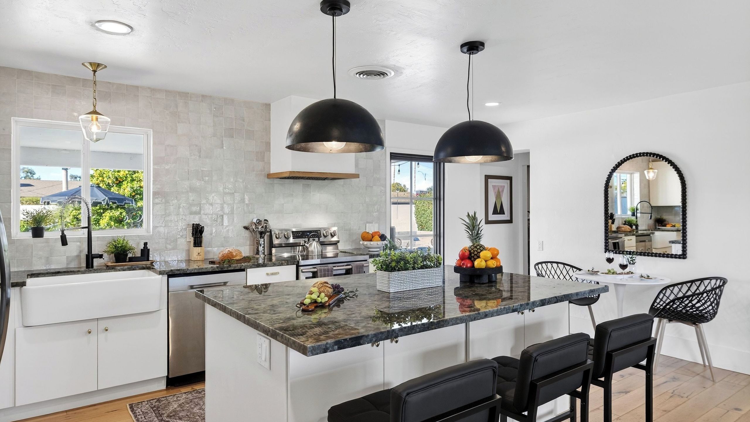 A modern kitchen with a central island, pendant lighting, and a view of the outdoors.