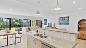 A modern kitchen with a large island, a dining area with a table and chairs, and a view of the outdoors. - Elsinor 4 Located a short stroll from Lake Mulwala and the popular local clubs. (Mulwala)