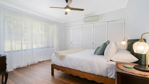 A bedroom with a bed, bedside table, lamp, ceiling fan, and window with sheer curtains. - Audrey's Of Beechworth NEW Listing (Beechworth)