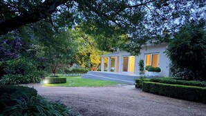 A modern house with a gravel driveway, a well-maintained lawn, and a large tree in the background. - Clare Valley vineyard - Pool and walk to wineries - perfect for groups (Sevenhill)