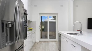 A modern kitchen with a stainless steel refrigerator, white cabinetry, and a built-in dishwasher. - Clare Valley vineyard - Pool and walk to wineries - perfect for groups (Sevenhill)