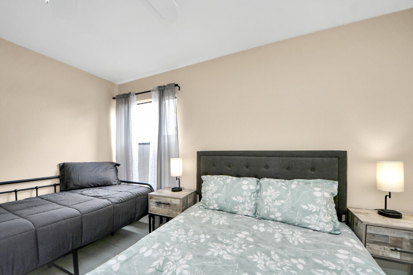Camera d'albergo con un letto, una poltrona, un comodino, una lampada e una finestra con tende.