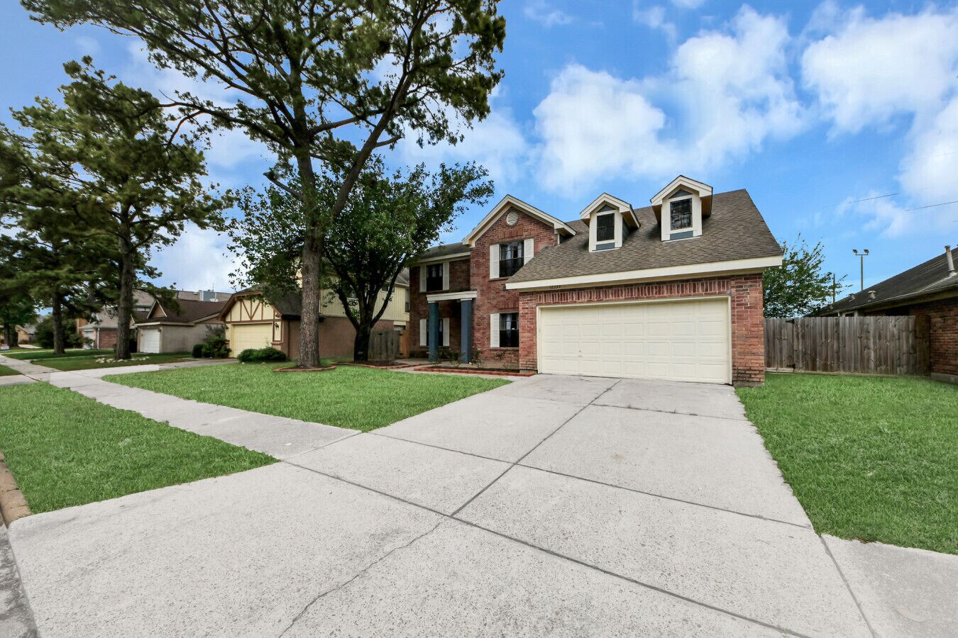 A two-story residential house with a garage, a front yard with grass, and a sidewalk.