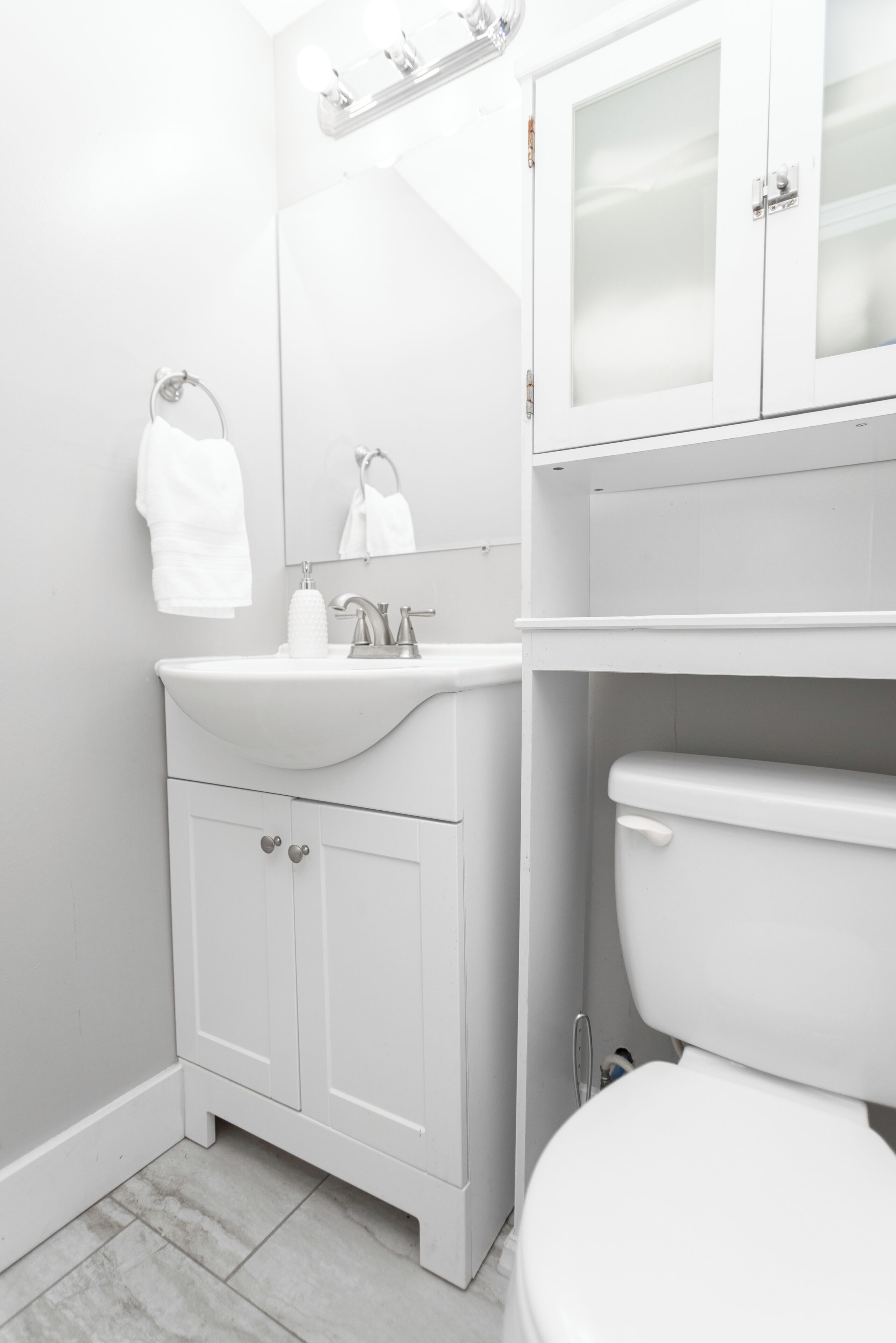 Une salle de bain blanche avec un lavabo, un miroir et des toilettes.