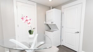 Una habitación moderna con una mesa de vidrio, una planta en maceta y lavadora secadora integradas.
