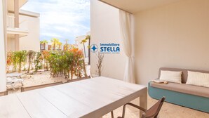 Ein Balkon mit Tisch, einer Couch, einem Schild mit der Aufschrift 'immobiliare STELLA' und Blick auf ein Gebäude sowie Pflanzen.