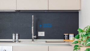 Eine Küche mit einem modernen Wasserhahn, einer Tafel mit einem Logo und einem Regal mit Gläsern.