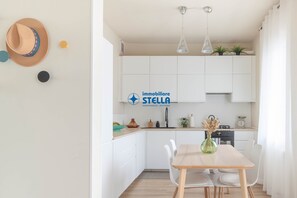 Une cuisine moderne avec des meubles blancs, une table à manger et un luminaire suspendu.