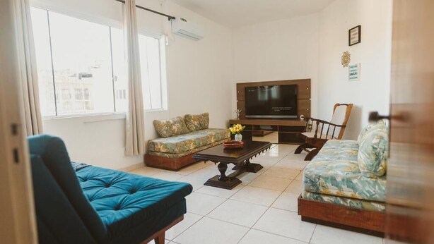 A living room with a sofa, a chair, a coffee table, and a television.