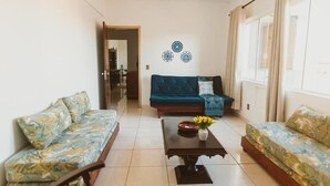 A living room with a sofa, a coffee table with a vase, and a wall with decorative patterns.