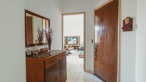 A hallway with a wooden door, a mirror, and a cabinet with decorative items.
