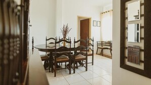 A dining area with a round table, wooden chairs, and a vase of dried plants.