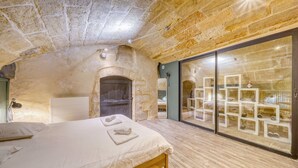 A bedroom with a stone ceiling, a wooden bed, a large sliding glass door, and a mirror. - A superb large loft in the heart of Bordeaux (Bordeaux)