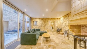 A modern living room with a stone wall, a green sofa, a small table, and a fireplace. - A superb large loft in the heart of Bordeaux (Bordeaux)