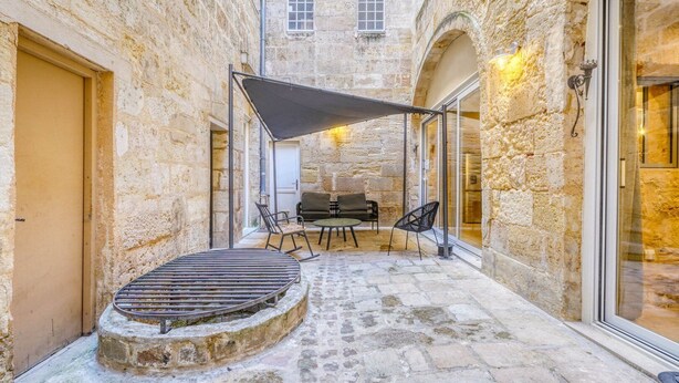 A stone courtyard with a grill table, chairs, and a canopy. - A superb large loft in the heart of Bordeaux (Bordeaux)