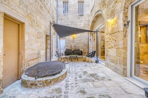 A stone courtyard with a grill table, chairs, and a canopy. - A superb large loft in the heart of Bordeaux (Bordeaux)
