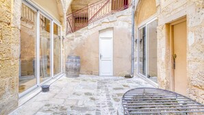 A stone courtyard with a white door, a wooden barrel, and a metal bench. - A superb large loft in the heart of Bordeaux (Bordeaux)