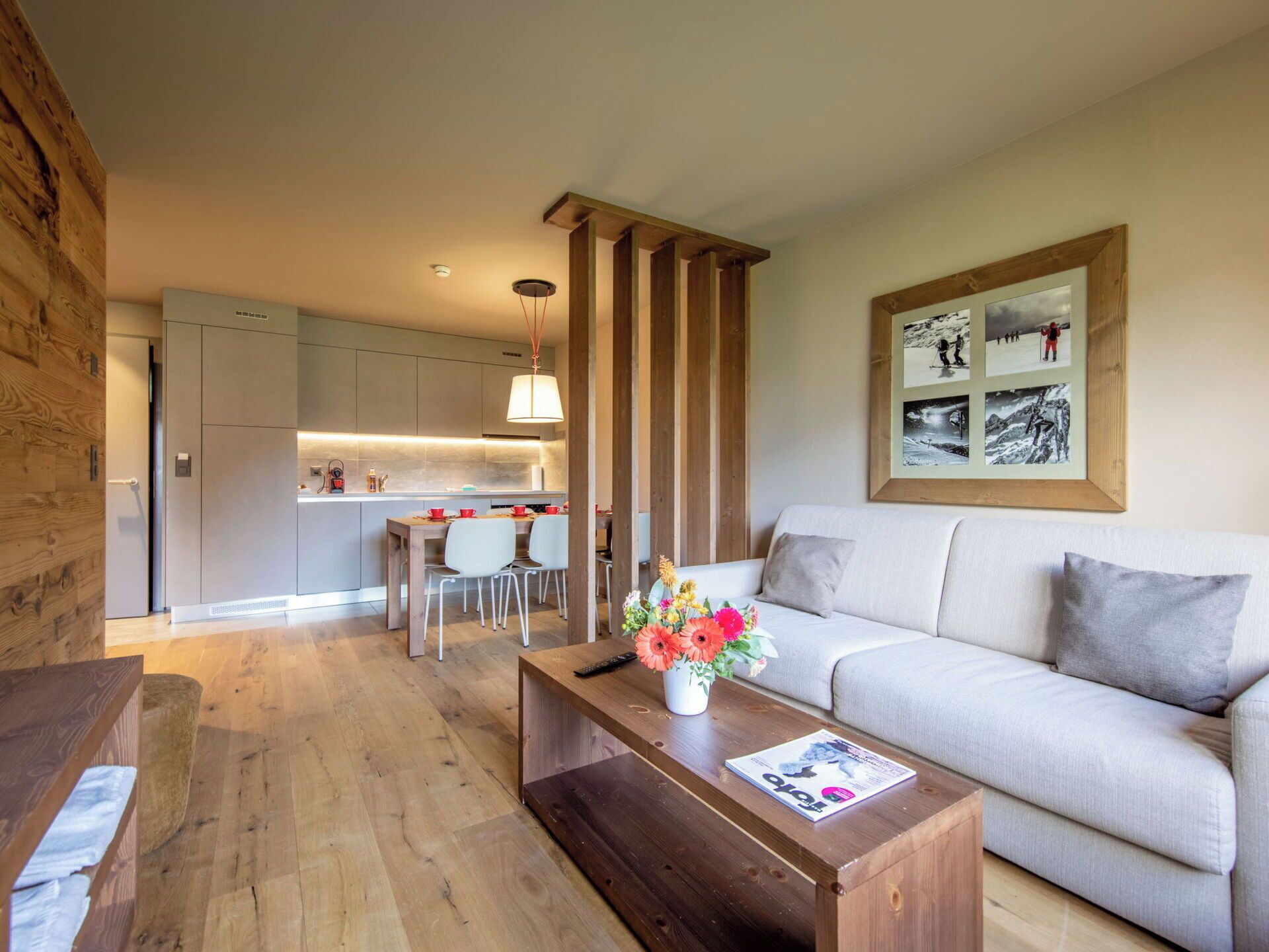 Ein modernes Wohnzimmer mit Holzboden, einer Couch, einem Couchtisch mit einer Zeitschrift und einem Essbereich mit Stühlen und einem Tisch.