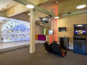 Une pièce équipée d’un mur d’escalade, d’un fauteuil de massage et d’une console de jeux.