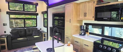 Una cocina moderna con una isla central, electrodomésticos negros y armarios de madera.