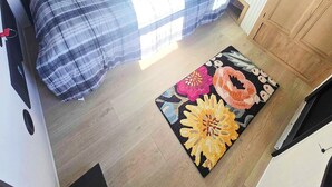 Quarto compacto de motorhome com cama, um pequeno espaço para sentar, televisão integrada e armários de madeira.