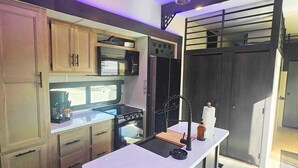 Uma cozinha moderna com armários de madeira, uma ilha central, forno embutido e micro-ondas.