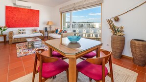 Un soggiorno moderno con tavolo da pranzo, mobili in vimini e vista sulla città.