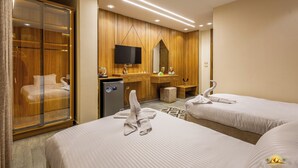 Habitación de hotel con dos camas, un armario, televisor y minibar.