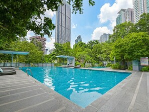A swimming pool with a tiled deck, surrounded by greenery and tall buildings. - Suasana Suites Bukit Ceylon - Pavillion (Kuala Lumpur)