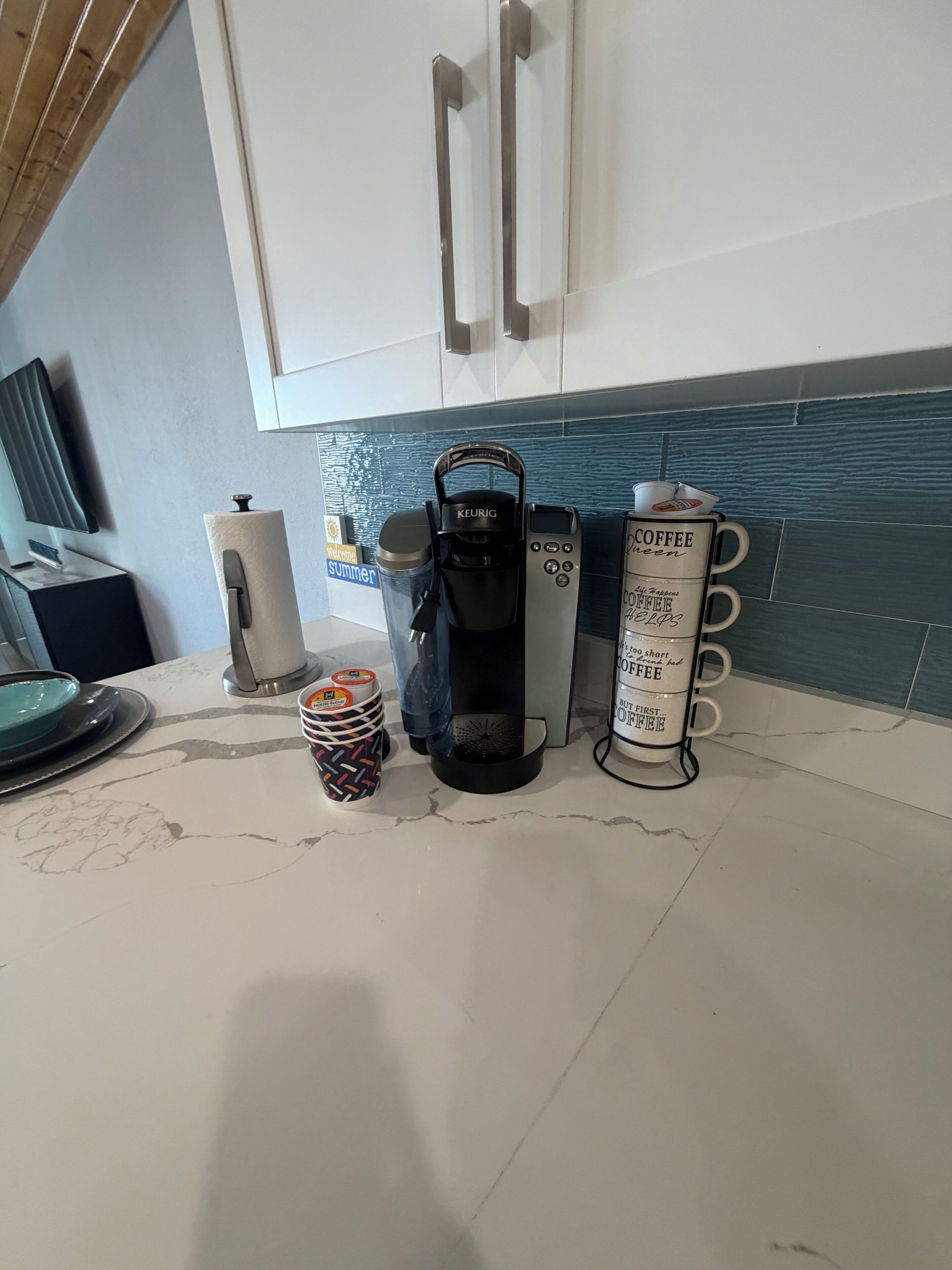 Eine Küchenarbeitsplatte mit Kaffeemaschine, einer Stapel Tassen und einem Mülleimer.