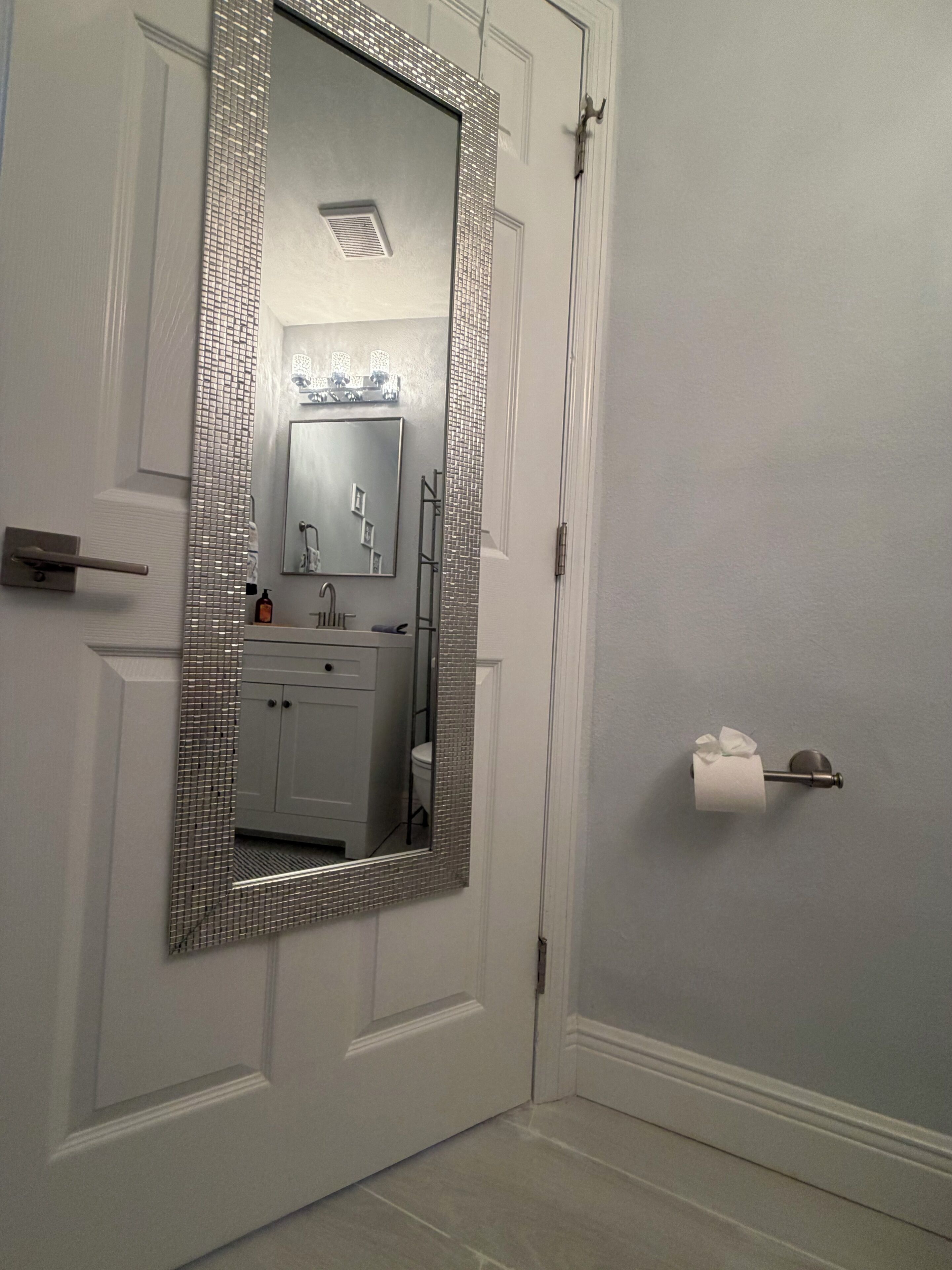 A bathroom with a large mirror, a toilet, a sink, and a towel rack.